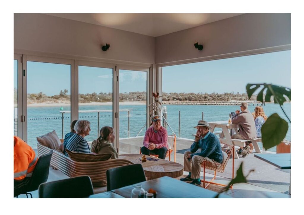 People enjoying view and meal at waterside cafe.